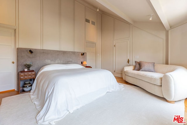 bedroom with light wood-type flooring and vaulted ceiling