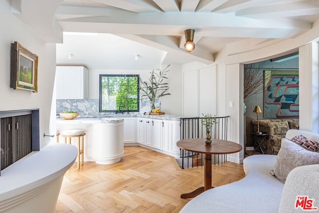 bar with decorative backsplash, light parquet floors, white cabinets, and light stone counters