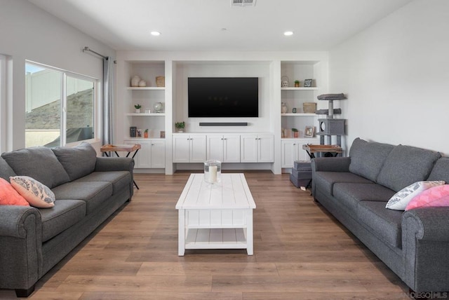 living room featuring built in shelves and hardwood / wood-style flooring