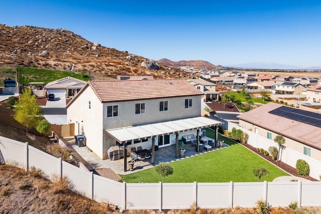 rear view of house featuring a mountain view, a yard, and a patio