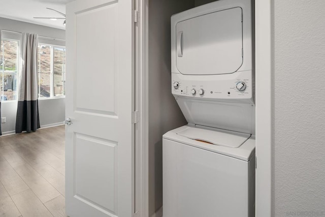 clothes washing area with ceiling fan, light hardwood / wood-style floors, and stacked washer and clothes dryer