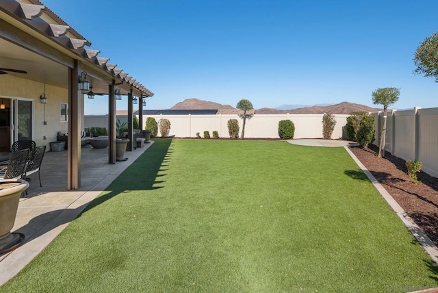 view of yard featuring a mountain view, ceiling fan, and a patio