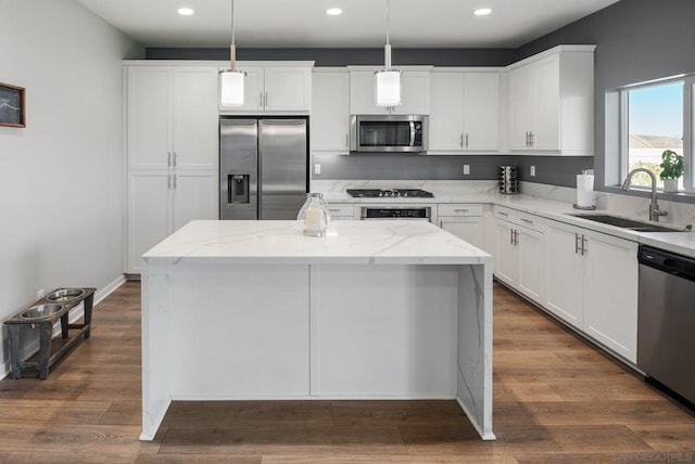 kitchen featuring light stone countertops, a center island, hanging light fixtures, stainless steel appliances, and white cabinets