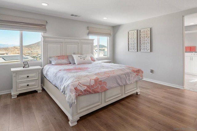 bedroom featuring a mountain view, dark hardwood / wood-style flooring, and connected bathroom