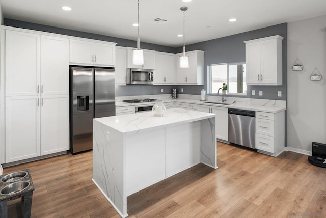 kitchen with stainless steel appliances, sink, decorative light fixtures, white cabinets, and a center island