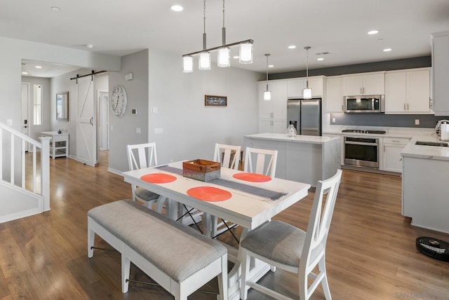 dining area featuring a barn door, sink, and light hardwood / wood-style flooring