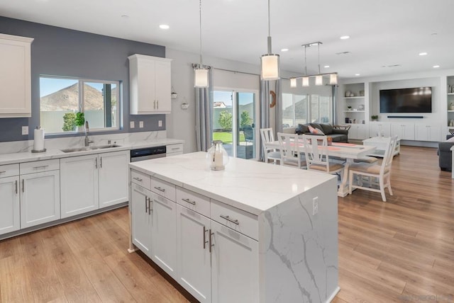 kitchen featuring a healthy amount of sunlight, white cabinetry, a kitchen island, and sink