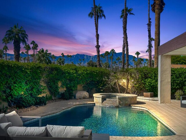 pool at dusk with a mountain view and an in ground hot tub