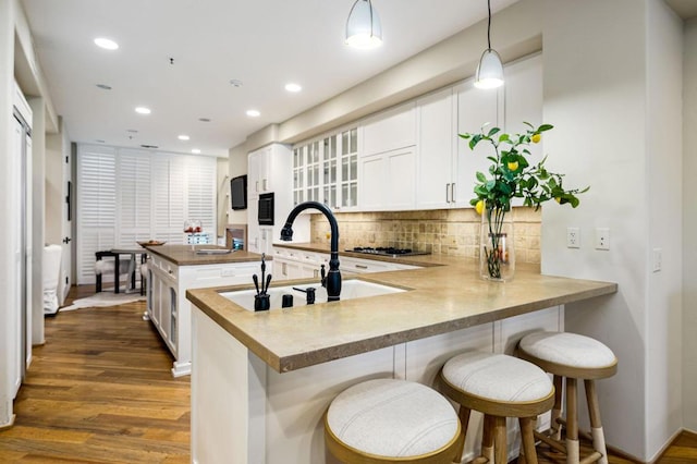 kitchen with hanging light fixtures, white cabinets, kitchen peninsula, and a breakfast bar area