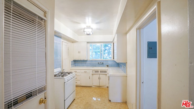 kitchen with backsplash, electric panel, white cabinets, sink, and white gas stove