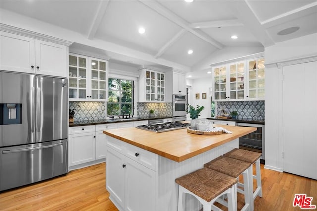 kitchen with white cabinetry, wood counters, light hardwood / wood-style flooring, backsplash, and appliances with stainless steel finishes