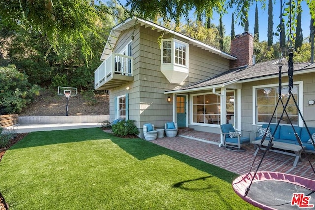 back of property featuring a yard, a balcony, and a patio