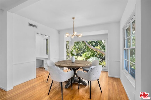 dining room with light hardwood / wood-style floors and an inviting chandelier