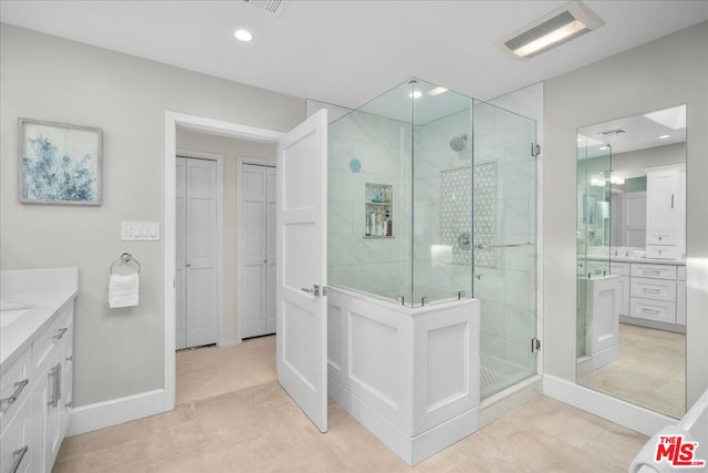 bathroom featuring tile patterned floors, vanity, and a shower with shower door