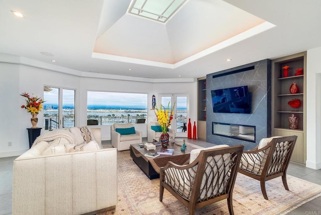 tiled living room featuring built in features, a raised ceiling, and a premium fireplace