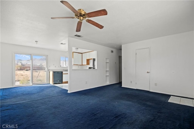 unfurnished living room with ceiling fan and dark carpet