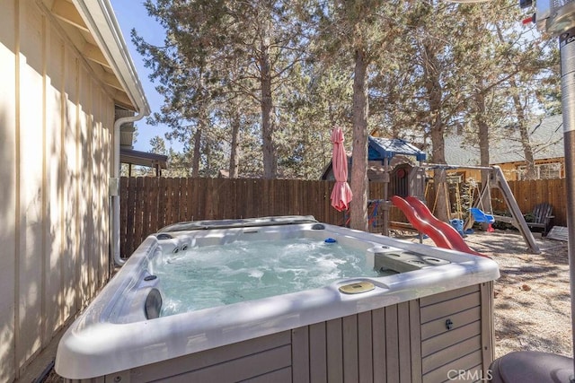 wooden terrace featuring a playground and a hot tub