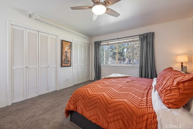 carpeted bedroom with ceiling fan and two closets