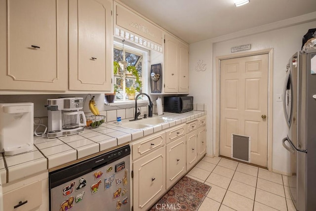 kitchen featuring tile countertops, light tile patterned floors, sink, and appliances with stainless steel finishes