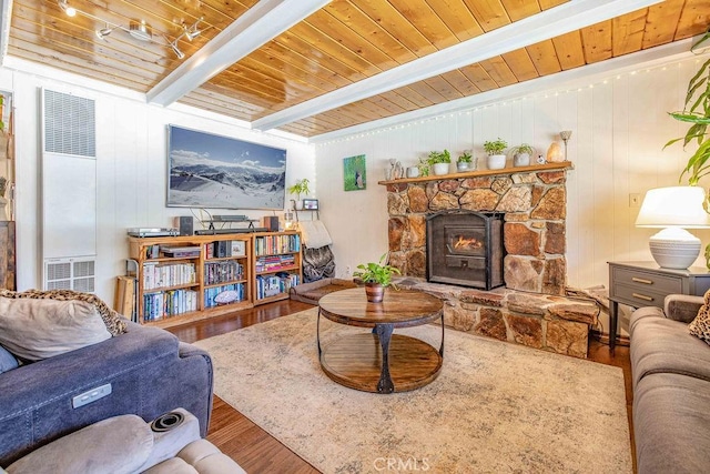 living room featuring hardwood / wood-style floors, wooden ceiling, a stone fireplace, wooden walls, and beamed ceiling