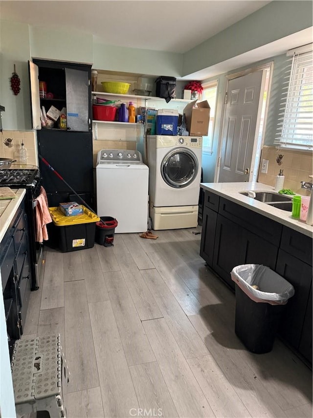 laundry area with sink, washer and dryer, and light wood-type flooring