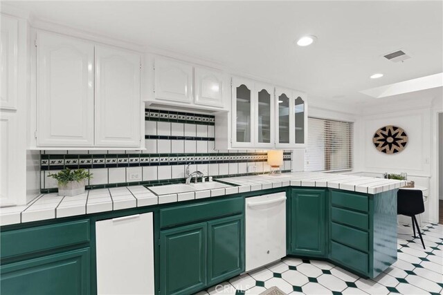 kitchen featuring kitchen peninsula, tile countertops, sink, and white cabinets