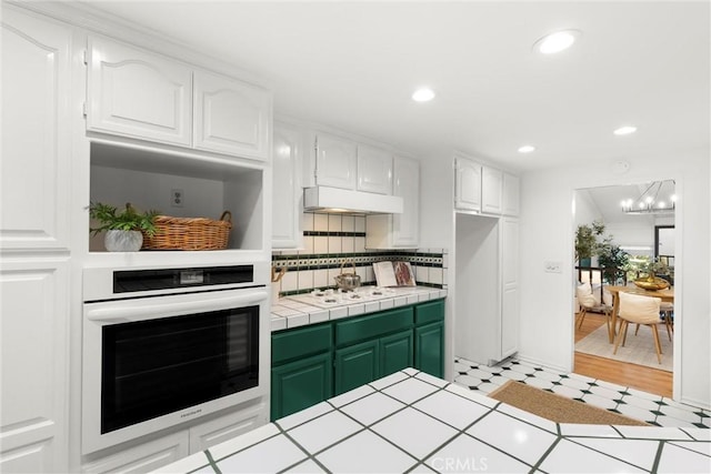 kitchen featuring tile counters, white gas cooktop, oven, white cabinets, and green cabinetry