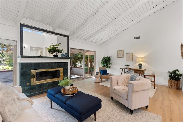 living room featuring a premium fireplace, high vaulted ceiling, a healthy amount of sunlight, and light wood-type flooring