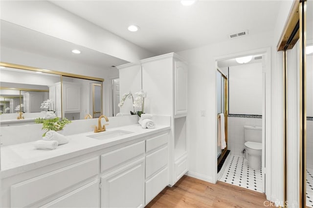 bathroom featuring vanity, wood-type flooring, tile walls, and toilet