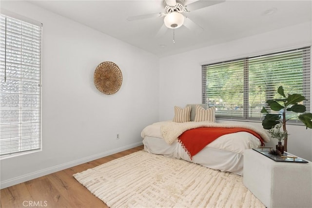 bedroom featuring multiple windows, ceiling fan, and light hardwood / wood-style flooring