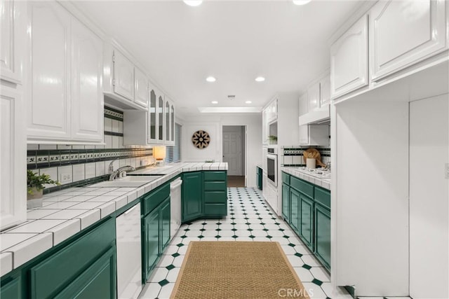 kitchen featuring backsplash, green cabinets, tile counters, white cabinetry, and stainless steel appliances