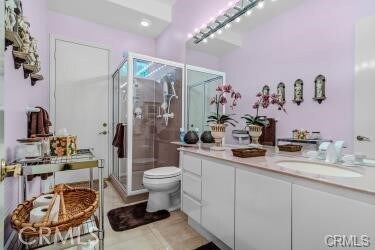 bathroom featuring tile patterned flooring, vanity, toilet, and walk in shower