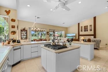 kitchen featuring kitchen peninsula, a center island, white cabinets, and stainless steel gas stovetop