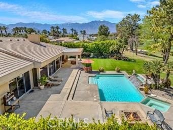 view of pool featuring a mountain view, a patio area, a yard, and an in ground hot tub