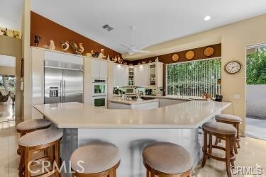 kitchen featuring built in fridge, a breakfast bar area, white cabinets, lofted ceiling, and light tile patterned flooring