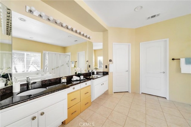 kitchen featuring sink, white cabinets, dark stone counters, and light tile patterned floors