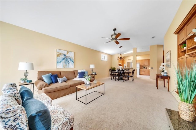 carpeted living room with ceiling fan with notable chandelier and vaulted ceiling