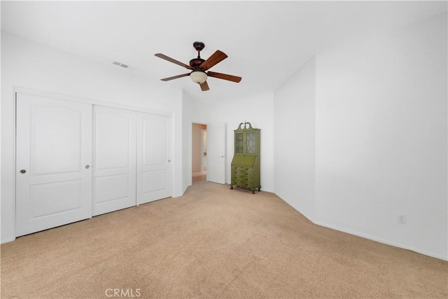 unfurnished bedroom with light carpet, a closet, and ceiling fan