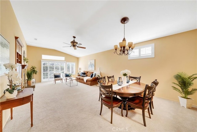 carpeted dining area featuring plenty of natural light, ceiling fan with notable chandelier, and vaulted ceiling