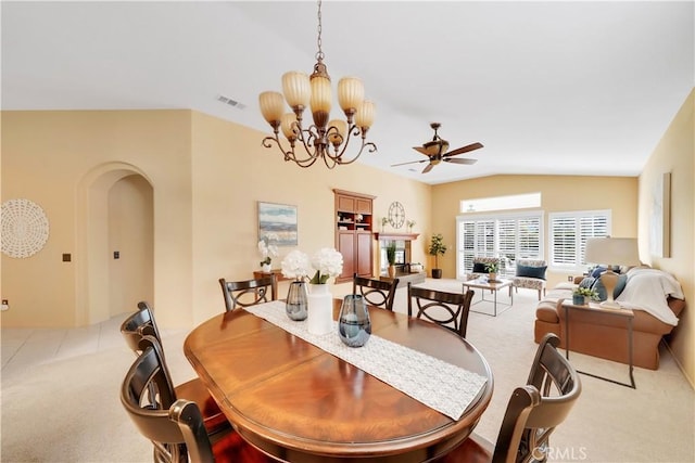 dining area featuring ceiling fan with notable chandelier, light colored carpet, and vaulted ceiling