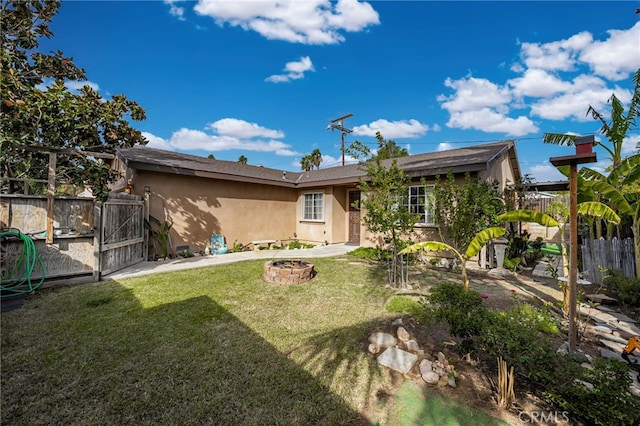 rear view of house with a yard and an outdoor fire pit