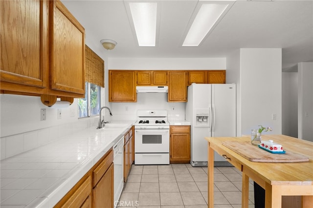 kitchen featuring tile counters, light tile patterned flooring, white appliances, and sink