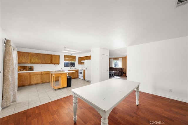 kitchen featuring light hardwood / wood-style flooring, a kitchen island, white appliances, and sink