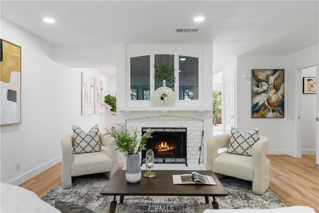 sitting room featuring wood-type flooring and a brick fireplace