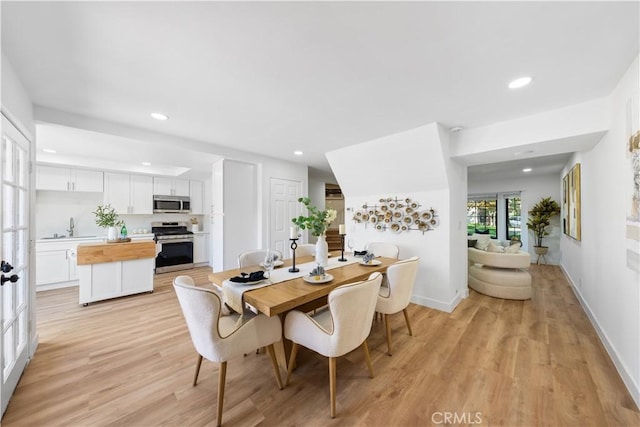 dining space with sink, french doors, and light wood-type flooring