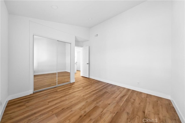 unfurnished bedroom featuring a closet, wood-type flooring, and vaulted ceiling