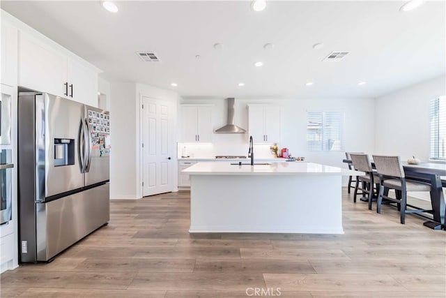 kitchen with white cabinets, a wealth of natural light, wall chimney exhaust hood, and appliances with stainless steel finishes