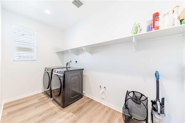 laundry area featuring washer and dryer and light hardwood / wood-style floors