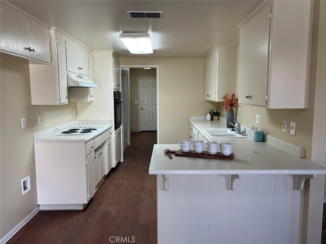 kitchen featuring a kitchen bar, dark hardwood / wood-style flooring, kitchen peninsula, and white cabinetry