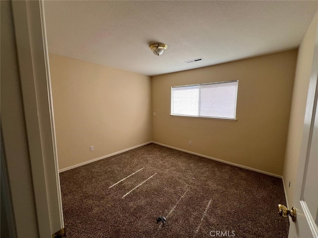 empty room with dark carpet and a textured ceiling